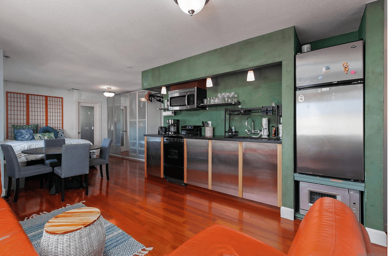 An open-concept condo with stainless appliances, green paint, and shiny wood floor